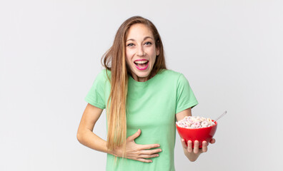 thin pretty woman laughing out loud at some hilarious joke and holding a breakfast bowl