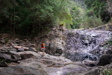 Bushwalker at rocky rainforest waterfall