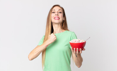 thin pretty woman feeling happy and facing a challenge or celebrating and holding a breakfast bowl