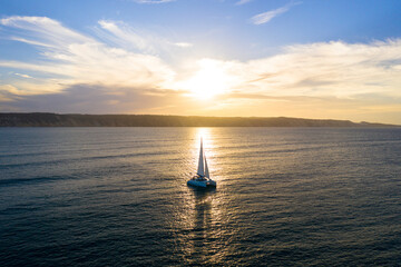 Catamaran sailing at sunset - obrazy, fototapety, plakaty