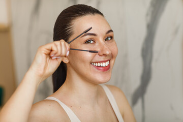 Smiling woman using eyebrow brush