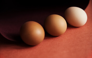 Chicken eggs are laid in a row on brown paper. Paper rolled into a spiral or oval. Easter eggs for the holiday.