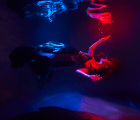 beautiful girl under the water in the light of the red moon