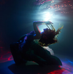 a woman dances underwater in a magical light