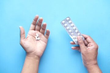 man's hand with medical pills and blister pack on blue 