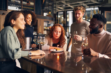 Woman blowing out birthday candle in bar