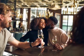 Man kissing woman in wine bar