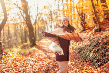 Woman having fun while walking through forest in autumn