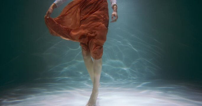 Beautiful healthy feet. Cinematic under water view, legs of young woman wearing stylish casual brown skirt slow motion