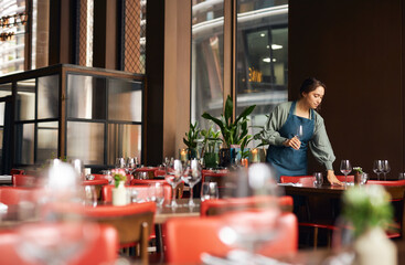 Female waitress setting tables - obrazy, fototapety, plakaty