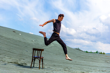 Guy jumping over chair in the desert