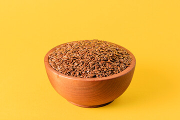 Flax seeds in a wooden bowl on a yellow background. Healthy eating. Organic product.