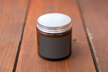 Label mockup of the glass jar with handmade candle on the wooden floor