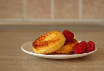 Homemade cheesecakes with cottage cheese with fresh raspberries on a beige background