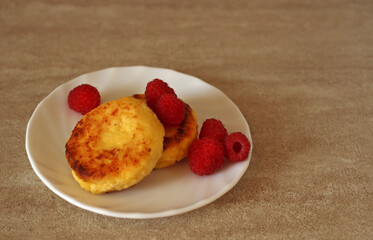 Homemade cheesecakes with cottage cheese with fresh raspberries on a beige background