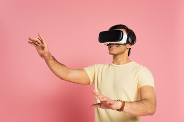 cheerful man in vr headset gesturing on pink