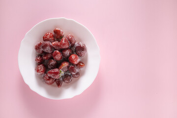 fresh strawberries in food film on a white plate. pink background. Concept of Recycling plastic and ecology. zero waste. Copy space