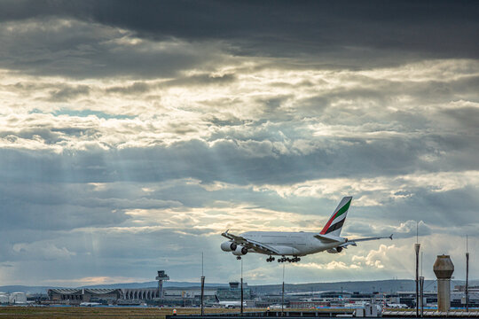 Picture of landing airplane at frankfurt airport in front of impressive sky with wild cloud formations and sun rays