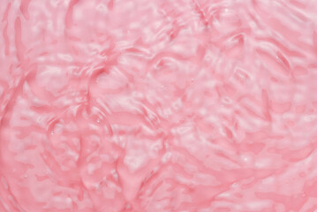 Fototapeta premium Waves and ripples on pink water close up, texture and creative background.