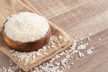 Fototapeta na wymiar Raw white rice in a wooden bowl over table.