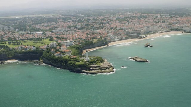 Aerial views of the french city biarritz in the south of France. The drone flys over the atlantic and is overlooking the scenic coast and shows tourist enjoy the beach of the spa town.