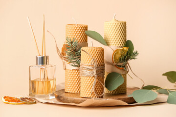 Handmade wax candles and reed diffuser on color background