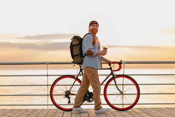 handsome bearded man traveling with bicycle in morning sunrise by the sea