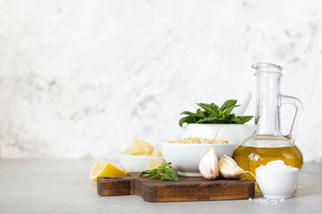 Ingredients for pesto on a marble table. Olive oil, basil, pine nuts, cheese.