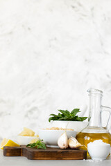 Ingredients for pesto on a marble table. Olive oil, basil, pine nuts, cheese.