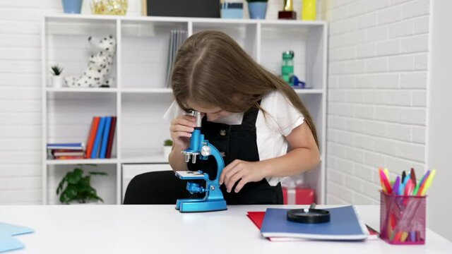 concentrated teen girl looking through modern scope on chemistry lesson, knowledge