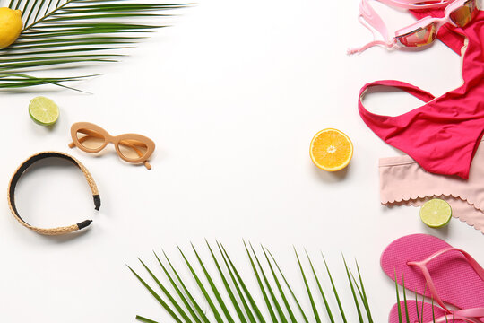 Composition with stylish swimsuit, beach accessories and palm leaves on white background