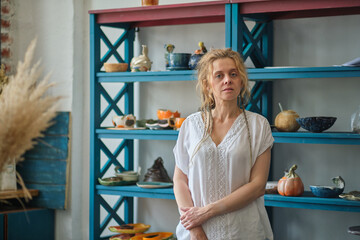 confident business owner posing in her office. in the background a wardrobe with ceramic dishes