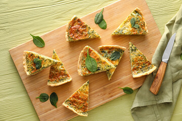 Board with pieces of tasty spinach tart on color wooden background