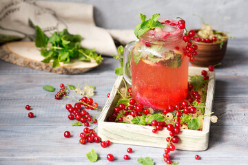 Cold drink on a wooden background. Lemonade with red currant and mint. Serving juice with ice and mint. A fresh crop of berries.