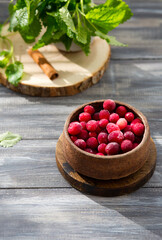 Frozen berries on a wooden table. Frosty cranberries with mint and cinnamon. Beautiful light from the window. Food Photography