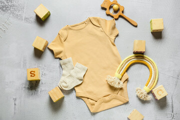Baby clothes and toys on light background