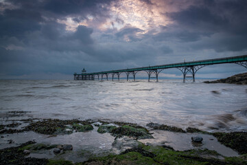 Fototapeta premium beach, blue, Clevedon Pier, clouds, coast, coastal, england, grey, moss, pebbles, pier, pools, puddles, rays, reflection, rocks, sand, sea, seaside, seaweed, sky, Somerset, structure, sun, sun rays, 