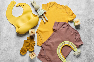 Baby clothes, bib and toys on light background