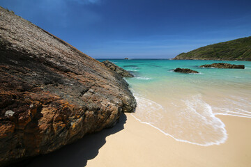 aqua water on the sand near a rock at the beach