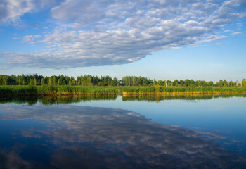 Beautiful calm blue landscape at the sunset of the lake. Reflection of clouds in the water