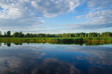 Beautiful calm blue landscape at the sunset of the lake. Reflection of clouds in the water