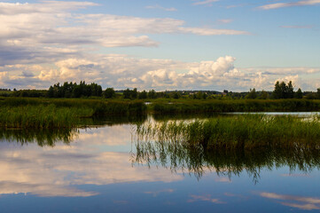 Beautiful calm blue landscape at the sunset of the lake. Reflection of clouds in the water