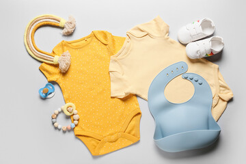 Baby clothes, shoes, toy and accessories on light background