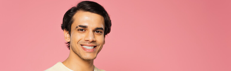 happy young man looking at camera and smiling isolated on pink, banner