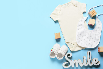 Composition with baby clothes, shoes and bib on color background