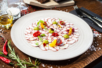 Octopus carpaccio. Spinach cream, cherry tomatoes. Delicious healthy Italian traditional food closeup served for lunch in modern gourmet cuisine restaurant