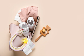 Box with baby clothes, shoes and accessories on color background