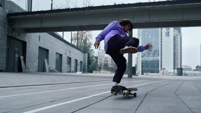 Sporty skater making trick on board outdoor. Skateboard rolling on asphalt. 