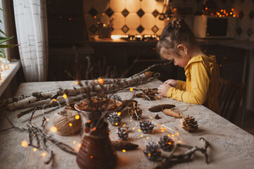 A cute sweet girl makes Christmas decorations from dried oranges, twigs and cones. Crafts for the holiday