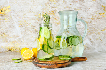 Bottle and jug with cucumber lemonade on grunge background